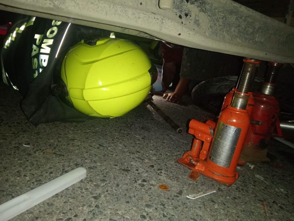 Bombero trabaja debajo del camión estabilizado con gatos hidráulicos.
