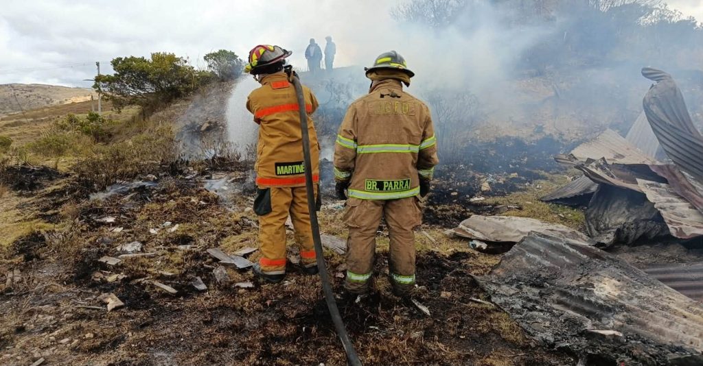 Dos unidades bomberiles inspeccionan el área afectada, rodeada de escombros y humo.