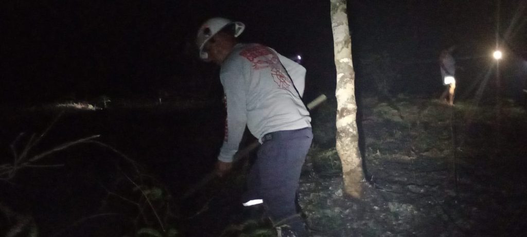 Personal operativo utiliza herramientas manuales para intervenir el terreno afectado por el incendio.