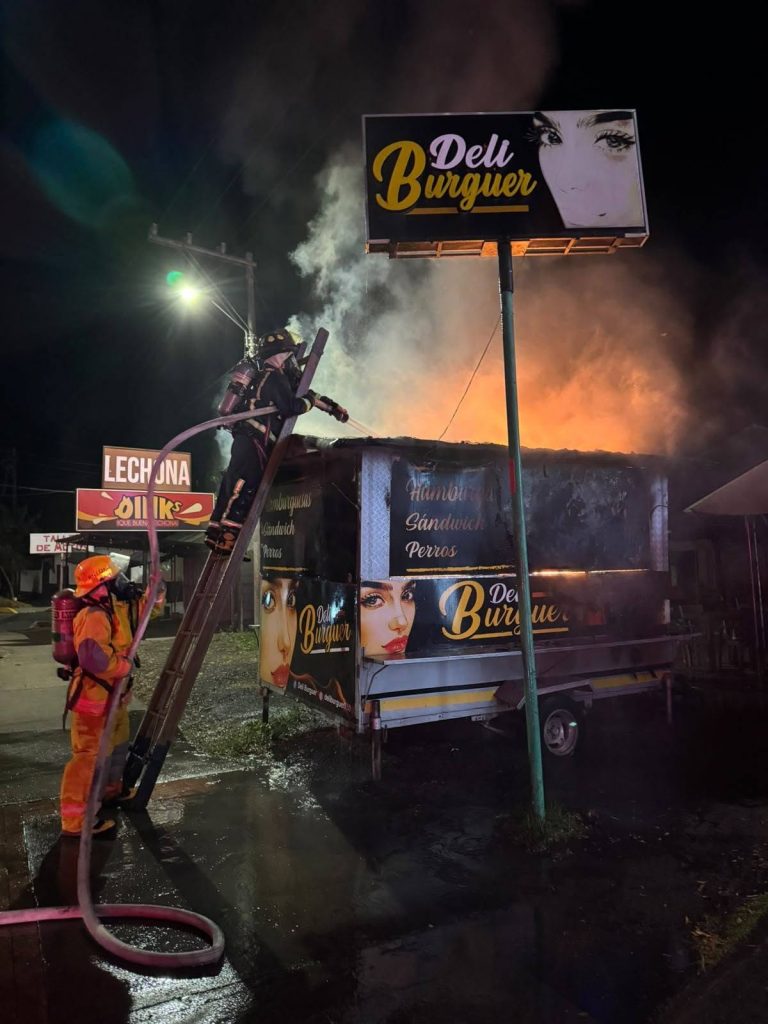 Atención nocturna del incendio en el remolque de comidas rápidas, con llamas y humo visibles en la parte superior.