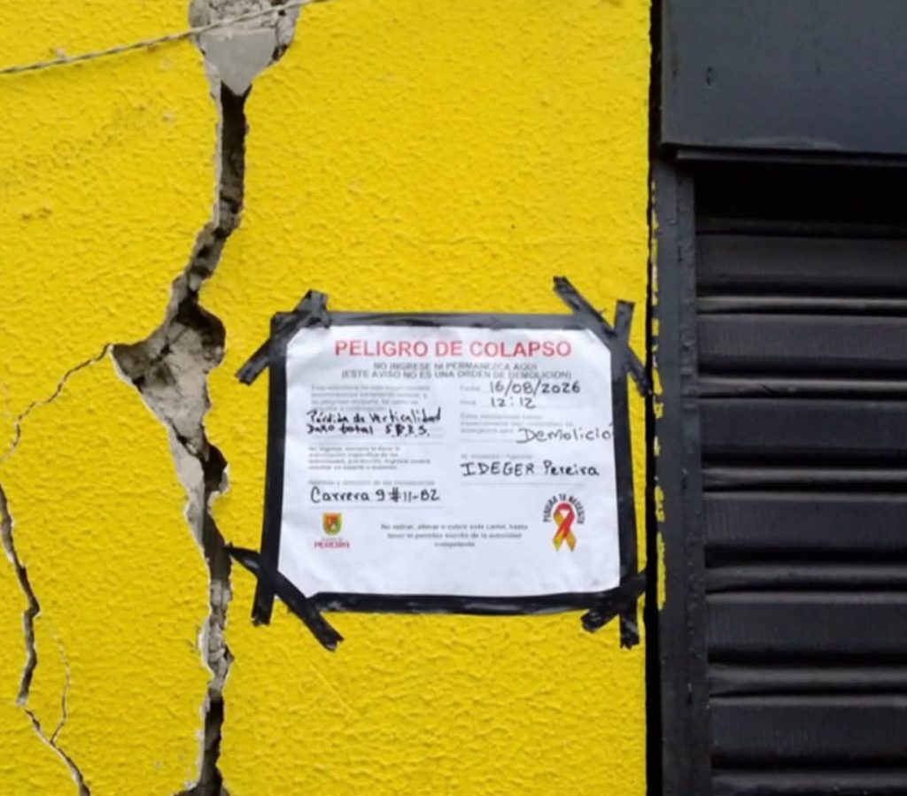 Grietas visibles en la fachada de la edificación, junto a un aviso preventivo relacionado con las condiciones de seguridad del inmueble.