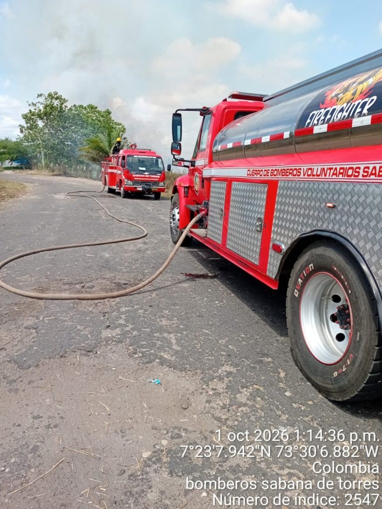 Máquinas del Cuerpo de Bomberos de Sabana de Torres permanecen desplegadas en la vía al Aeropuerto, con líneas de manguera instaladas para apoyar las labores de control y extinción.